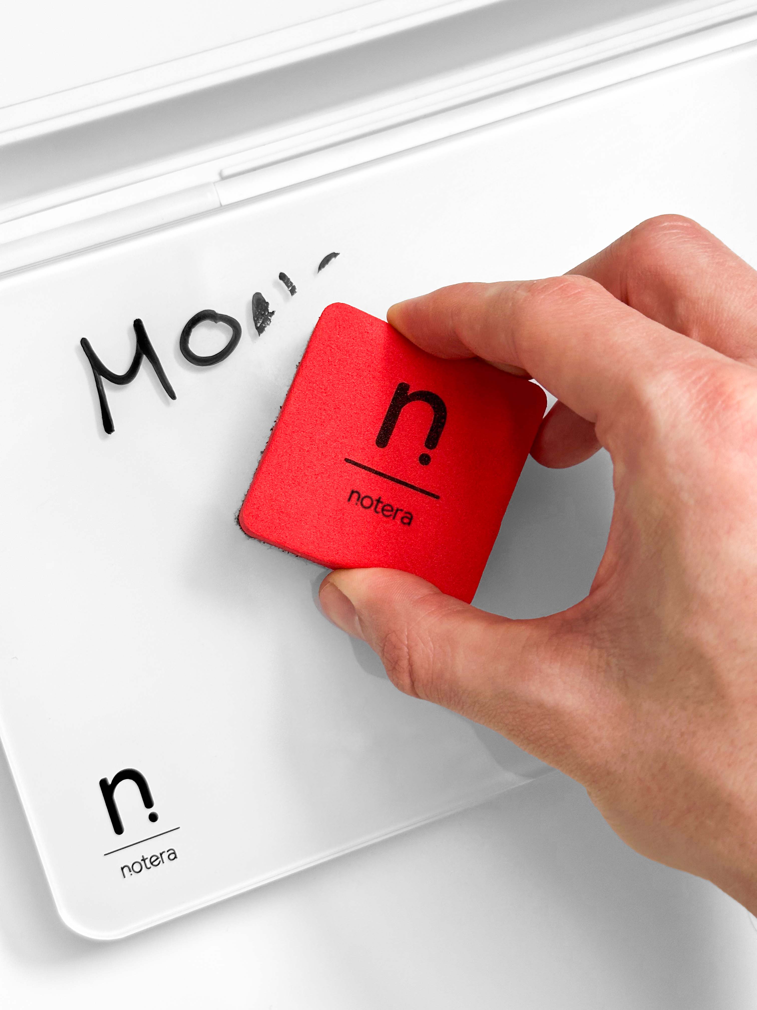 red eraser being used to erase writing on the whiteboard surface of a white wedge desk organiser