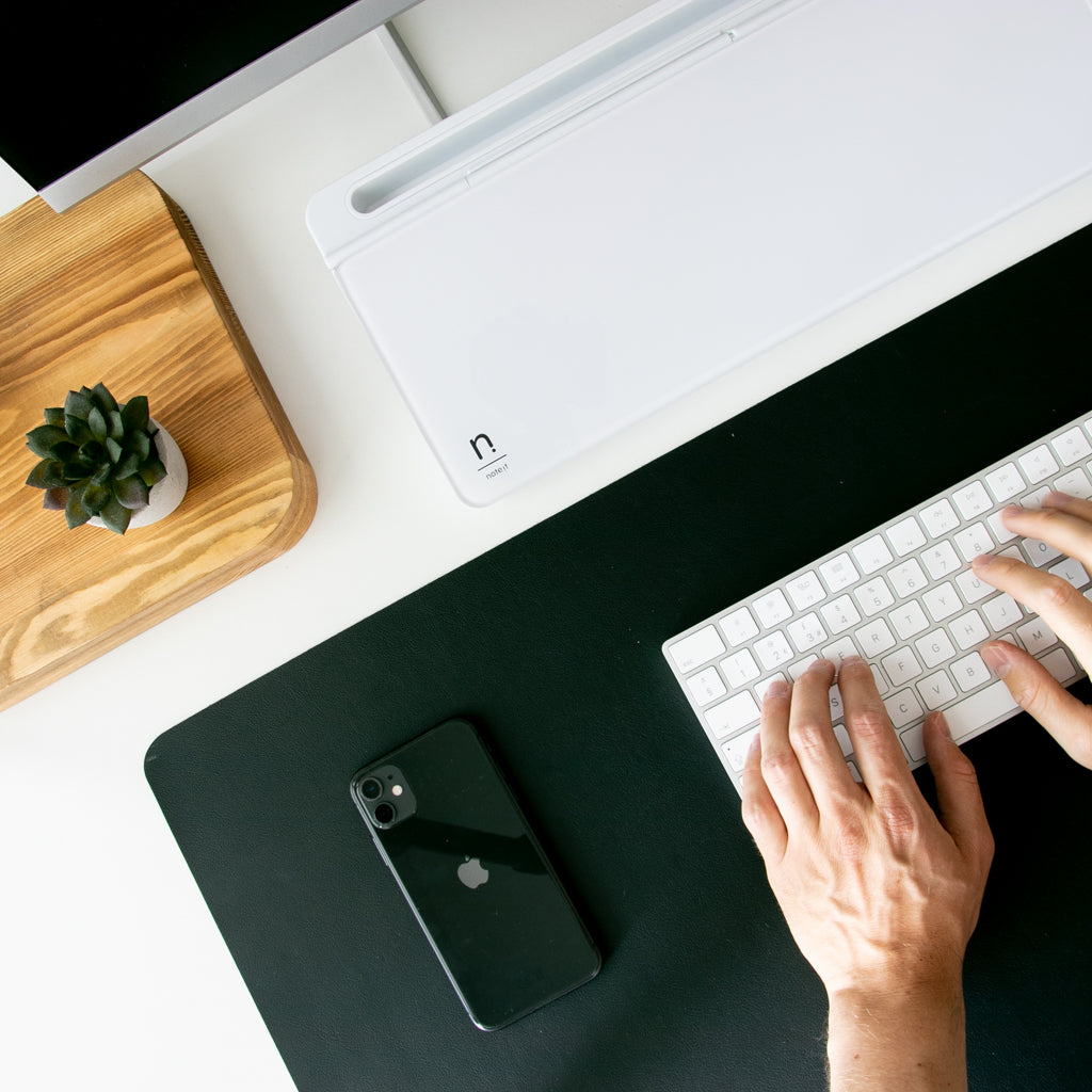 man typing on a keyboard with a white notera wedge on his desk
