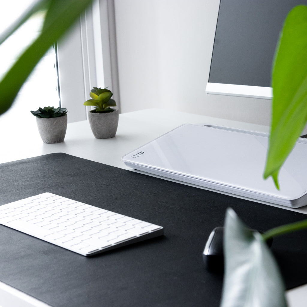 Desk setup with a brilliant white notera wedge located on the desk between the monitor and keyboard.