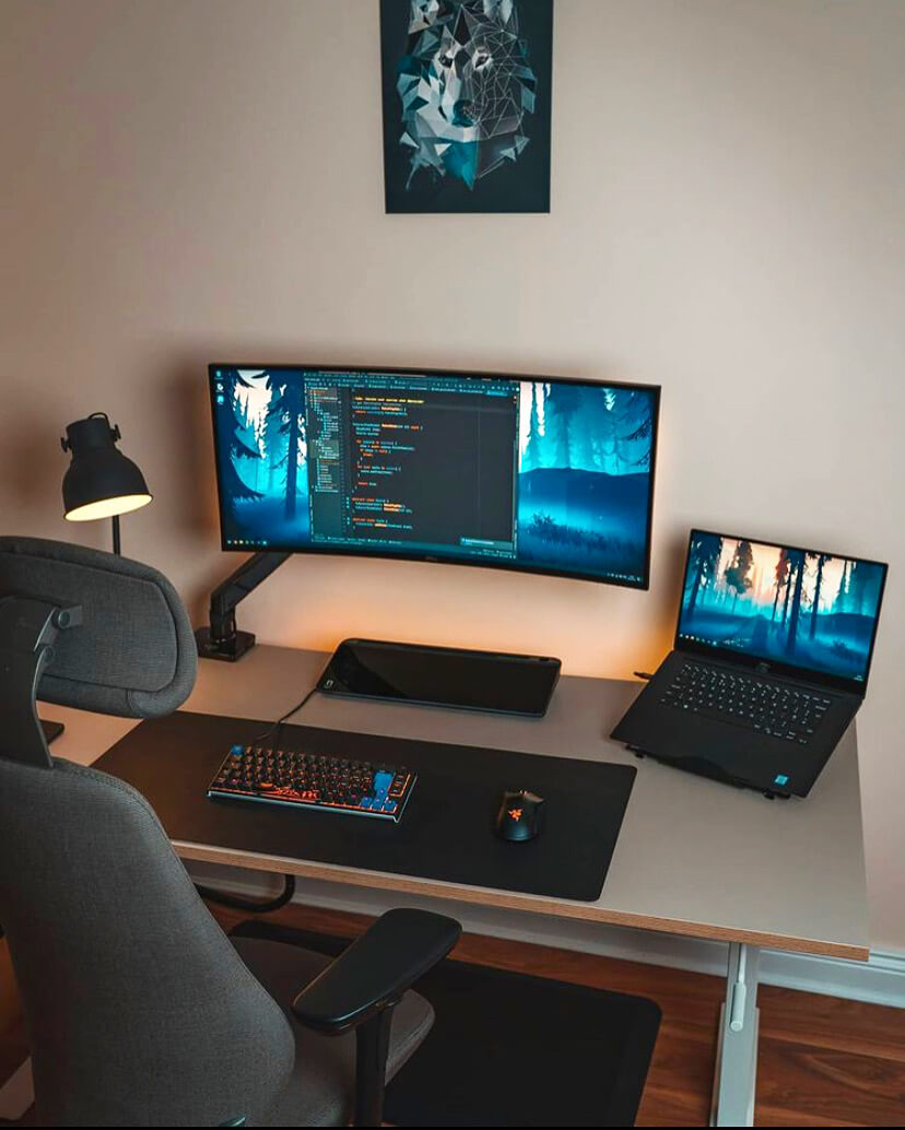 Desk setup with a midnight black notera wedge located underneath a monitor.